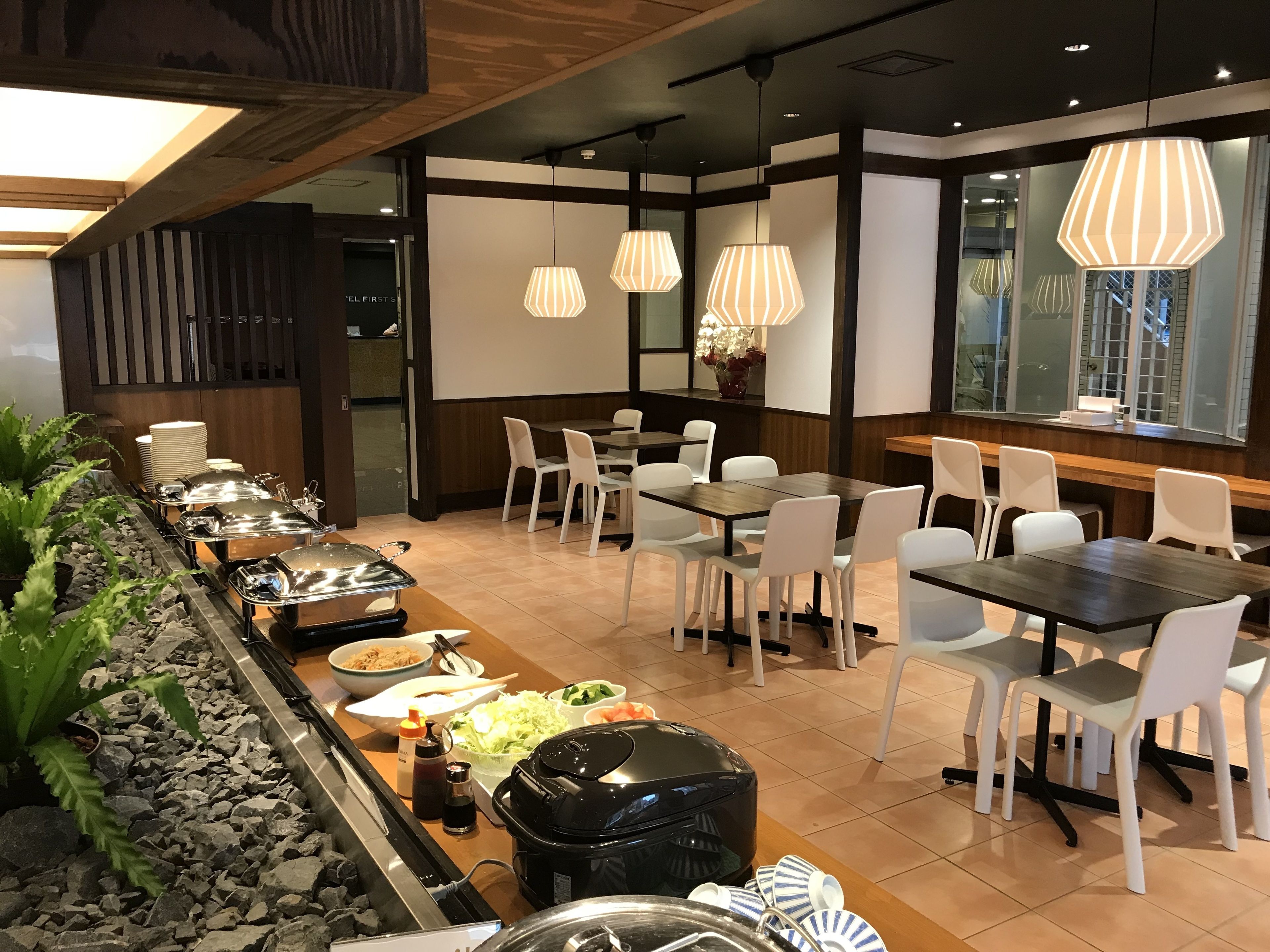 Un restaurante con una barra larga, sillas blancas y una estufa negra.
