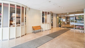 A clean, modern lobby with a bench, glass doors, and a tiled floor. - Hotel First Stay Amagasaki (Amagasaki)