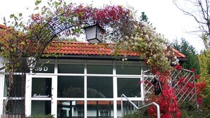 A restaurant with a tiled roof, large windows, and a staircase leading to the entrance. - Hotel Rodewisch (Rodewisch)