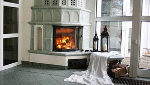 A fireplace with a visible fire, a bench with a white cloth, and a lantern. - Hotel Rodewisch (Rodewisch)