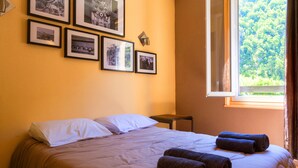 Een hotelkamer met een bed, kussens, handdoeken en ingelijste foto’s aan de muur.