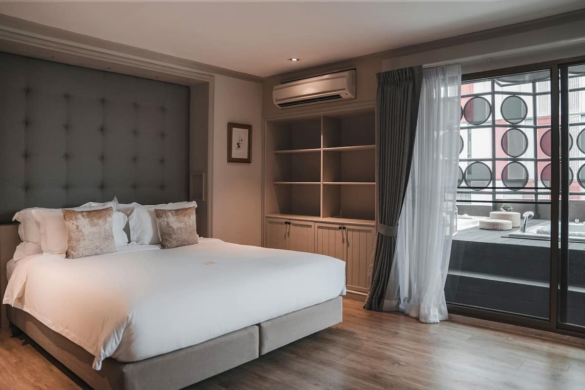 Ein Schlafzimmer mit einem großen Bett, einer Klimaanlage, einem eingebauten Kleiderschrank und Blick durch ein Fenster mit Rundfenstern.
