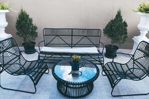 Une table ronde en verre, avec des chaises, un banc et des plantes en pot.