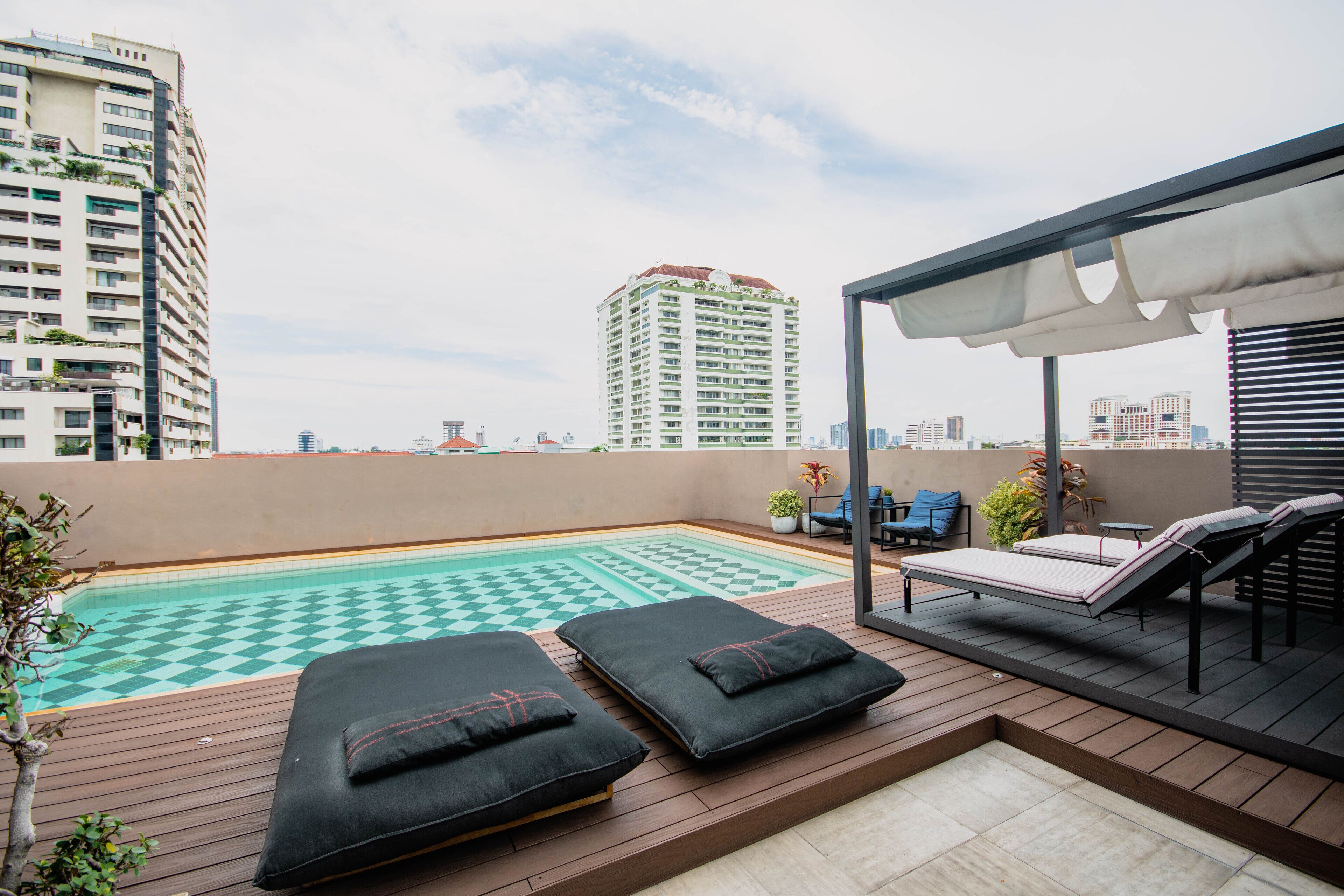 A rooftop pool area with lounge chairs and a checkered pool floor.