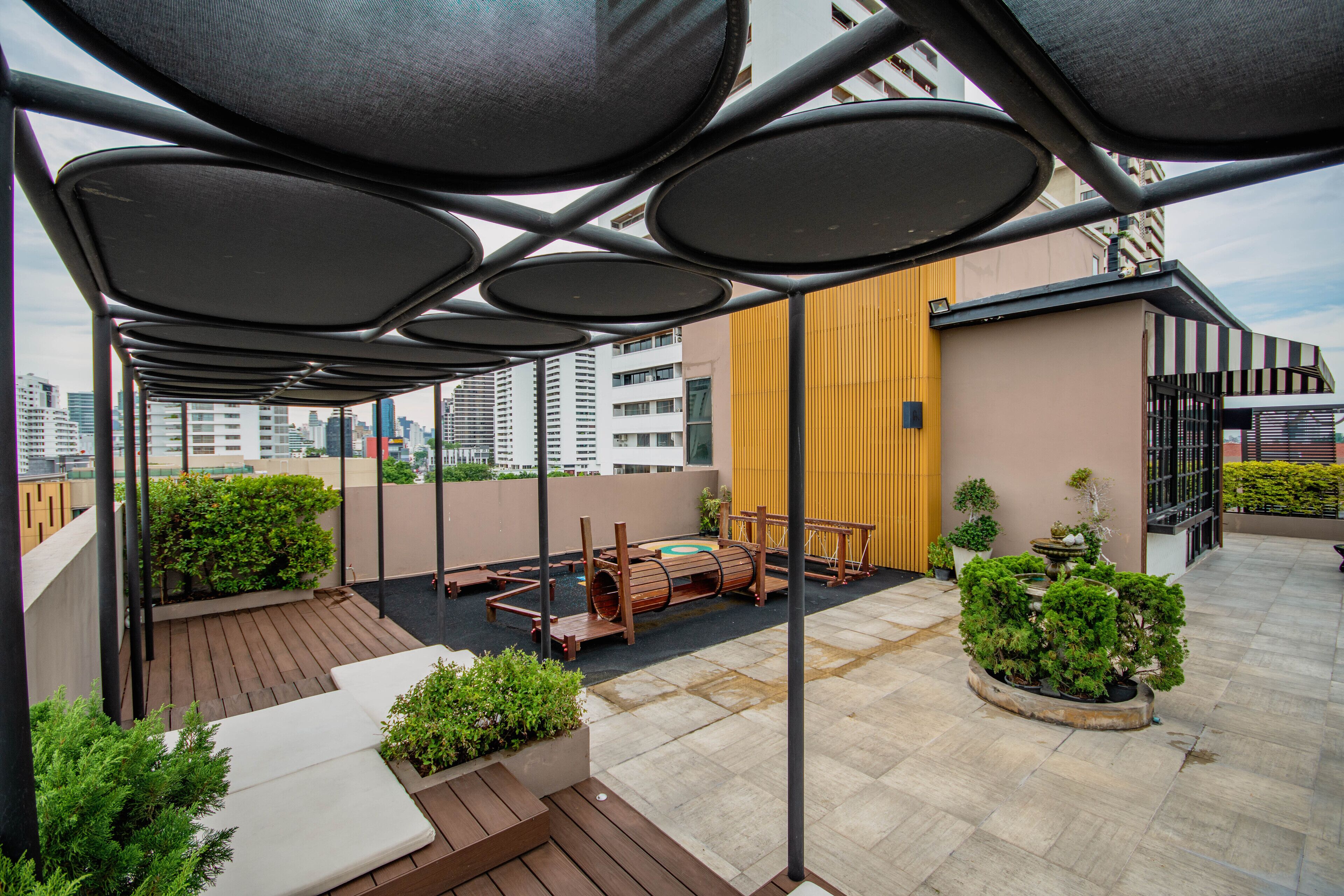 A rooftop terrace with a wooden deck, outdoor seating, and potted plants.