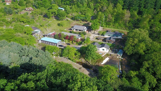 Vista aérea de una zona residencial con varias casas, una piscina y un invernadero.