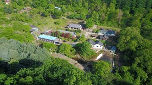 An aerial view of a residential area with multiple houses, a swimming pool, and a greenhouse. - Hwaya Mountain Pension (Gapyeong)