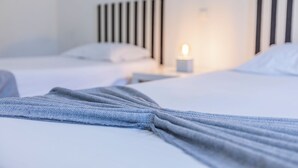 A hotel room with two beds, a bedside table with a lamp, and a blue blanket on one bed.