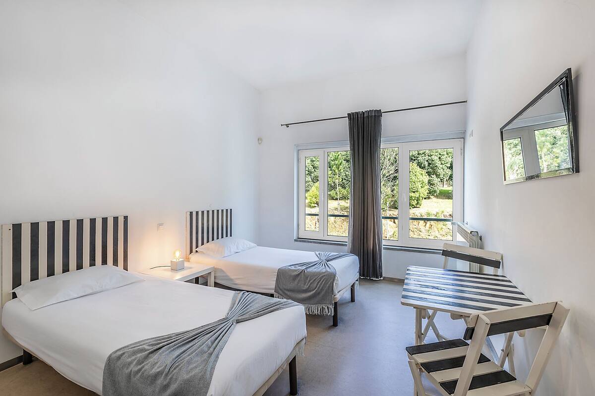 Ein Schlafzimmer mit zwei Betten, einem Tisch und einem Stuhl.