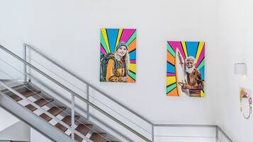 Un escalier avec des rampes en métal et un mur orné de deux œuvres d’art colorées.