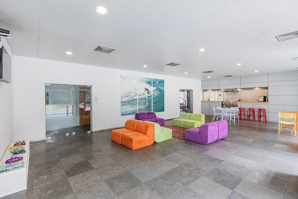 A modern interior with a seating area, a kitchen, and a view through a glass door.