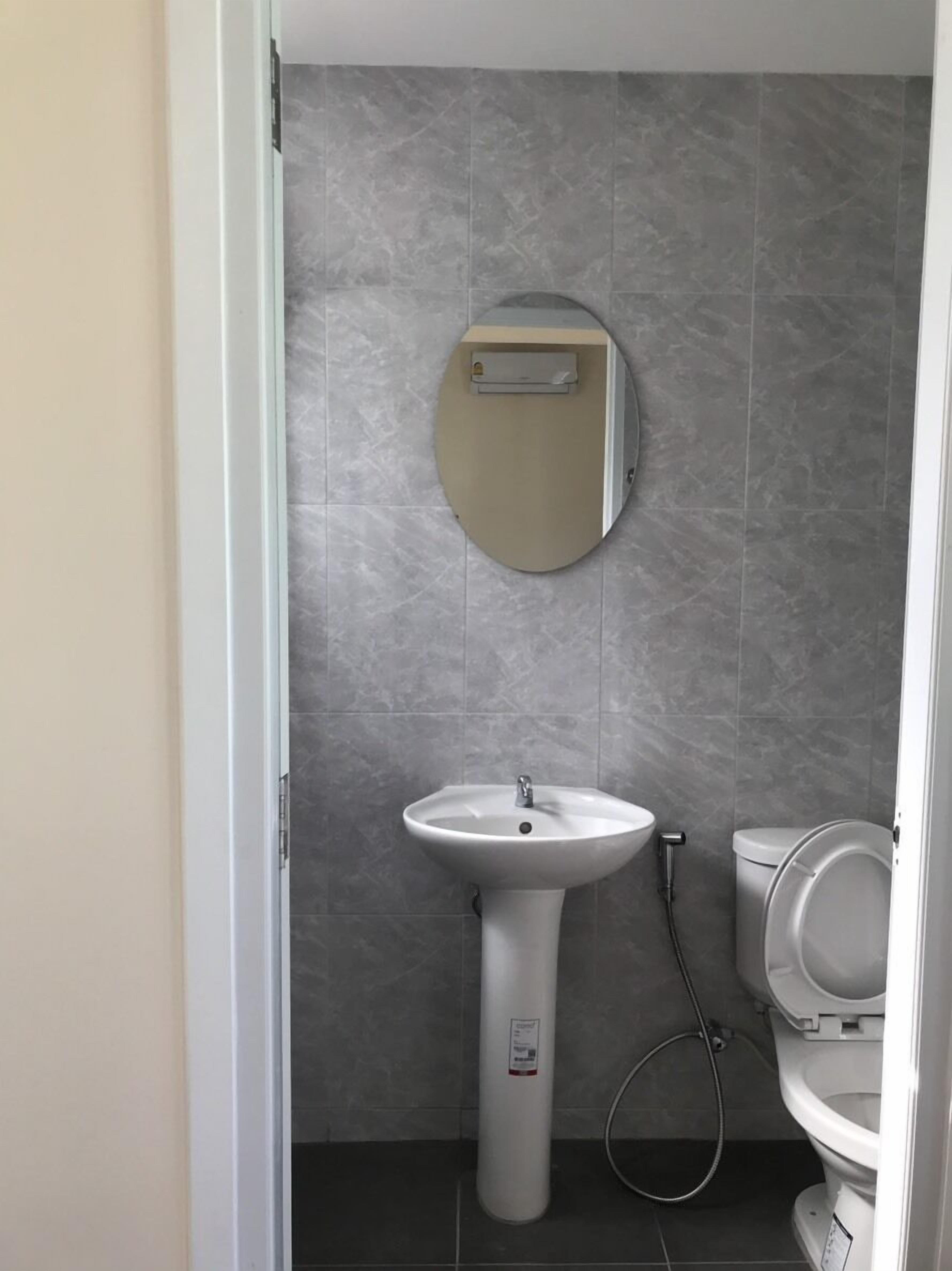 A bathroom with a pedestal sink, a toilet, and a mirror on the wall.