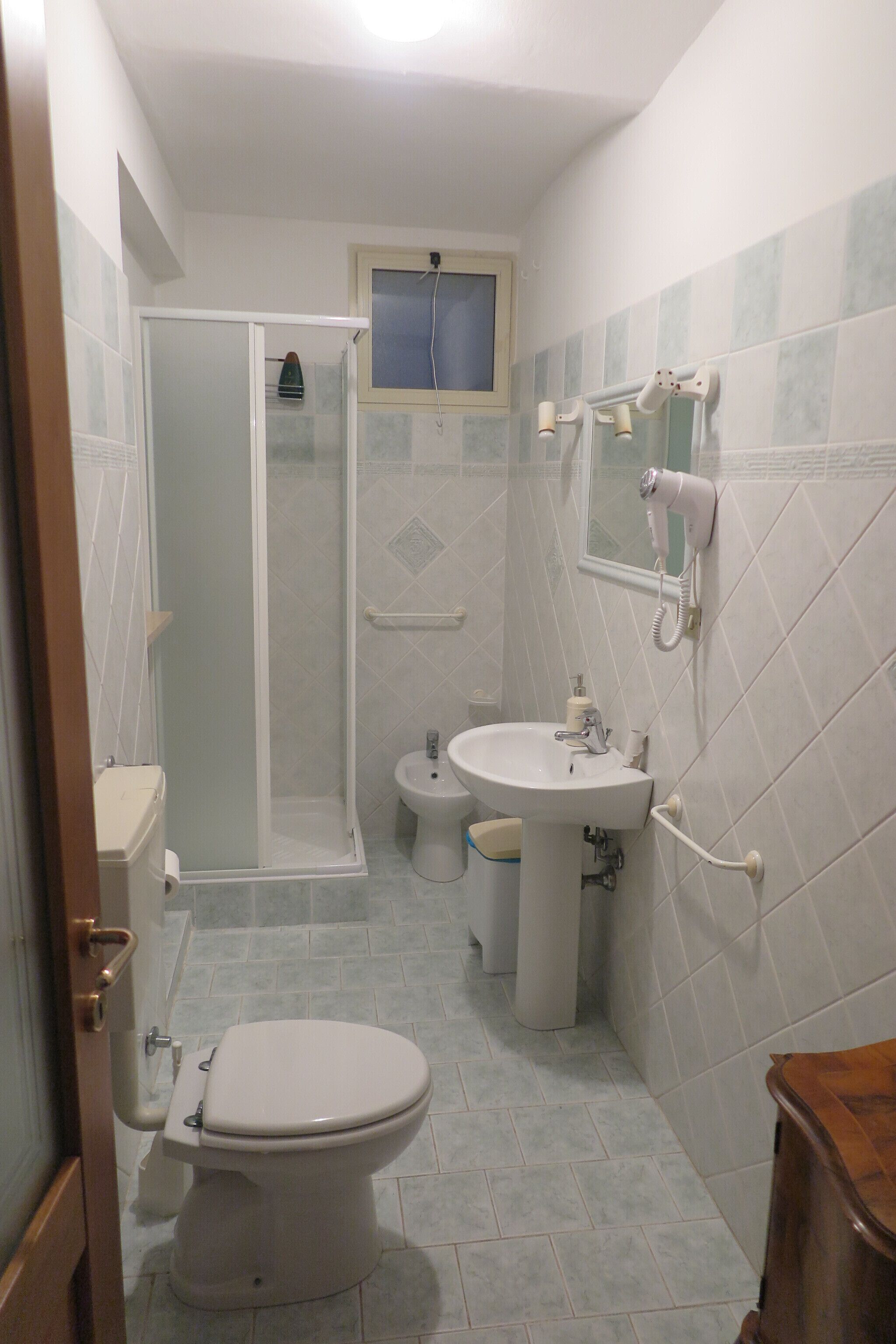 Et badeværelse med toilet, håndvask og bruser.