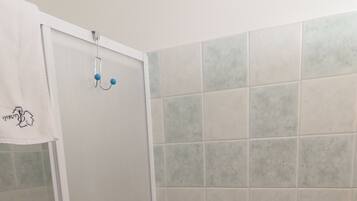 A bathroom with a toilet, a shower enclosure, and a sink.