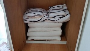A wooden wardrobe with a built-in shelf for folded bedding.