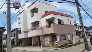 A multi-story residential building with a red roof, a fire hydrant sign, and a satellite dish.
