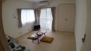 A room with a bed, a TV, a desk with a chair, and a wardrobe.