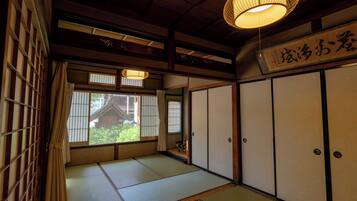 Een traditionele Japanse kamer met tatami vloerbedekking, schuifdeuren en een hanglamp.