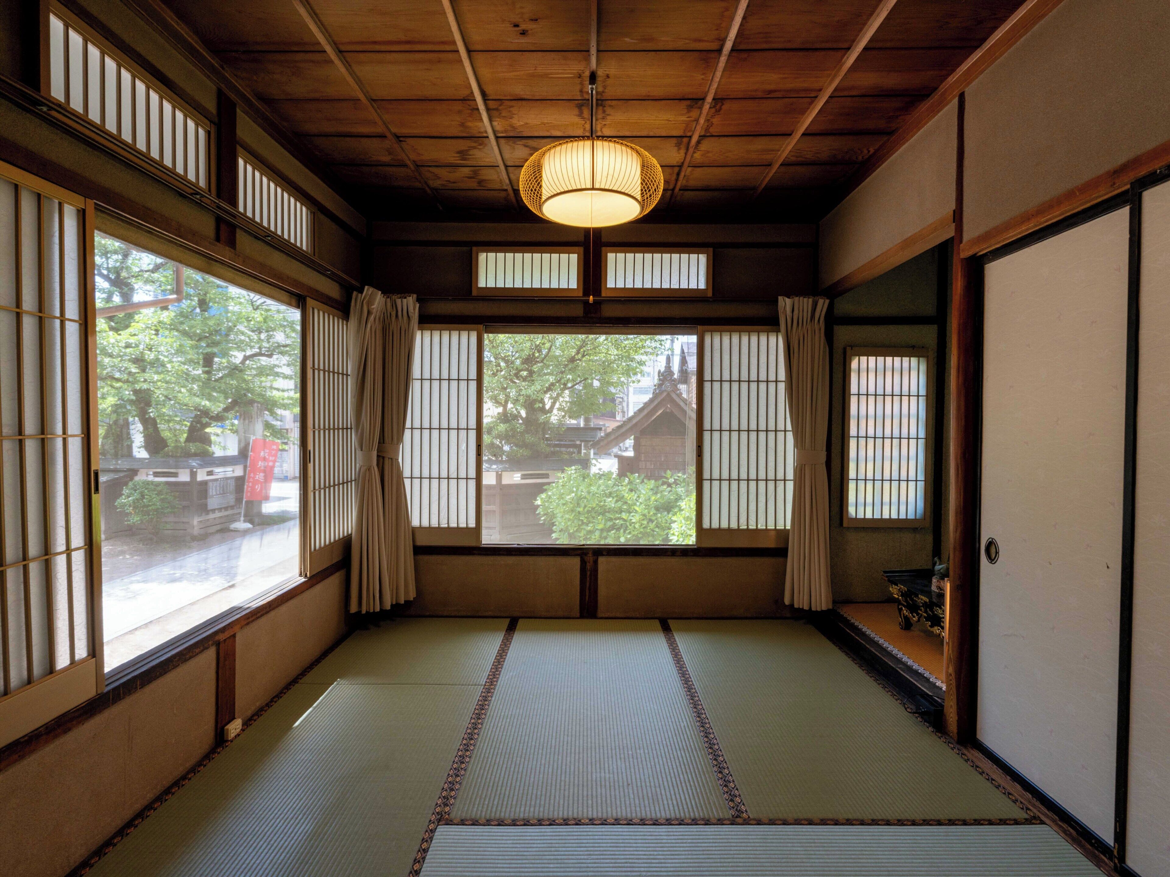 Ein traditioneller japanischer Raum mit Tatami-Boden, Shoji-Schirmen und einer hängenden Papierlaterne.