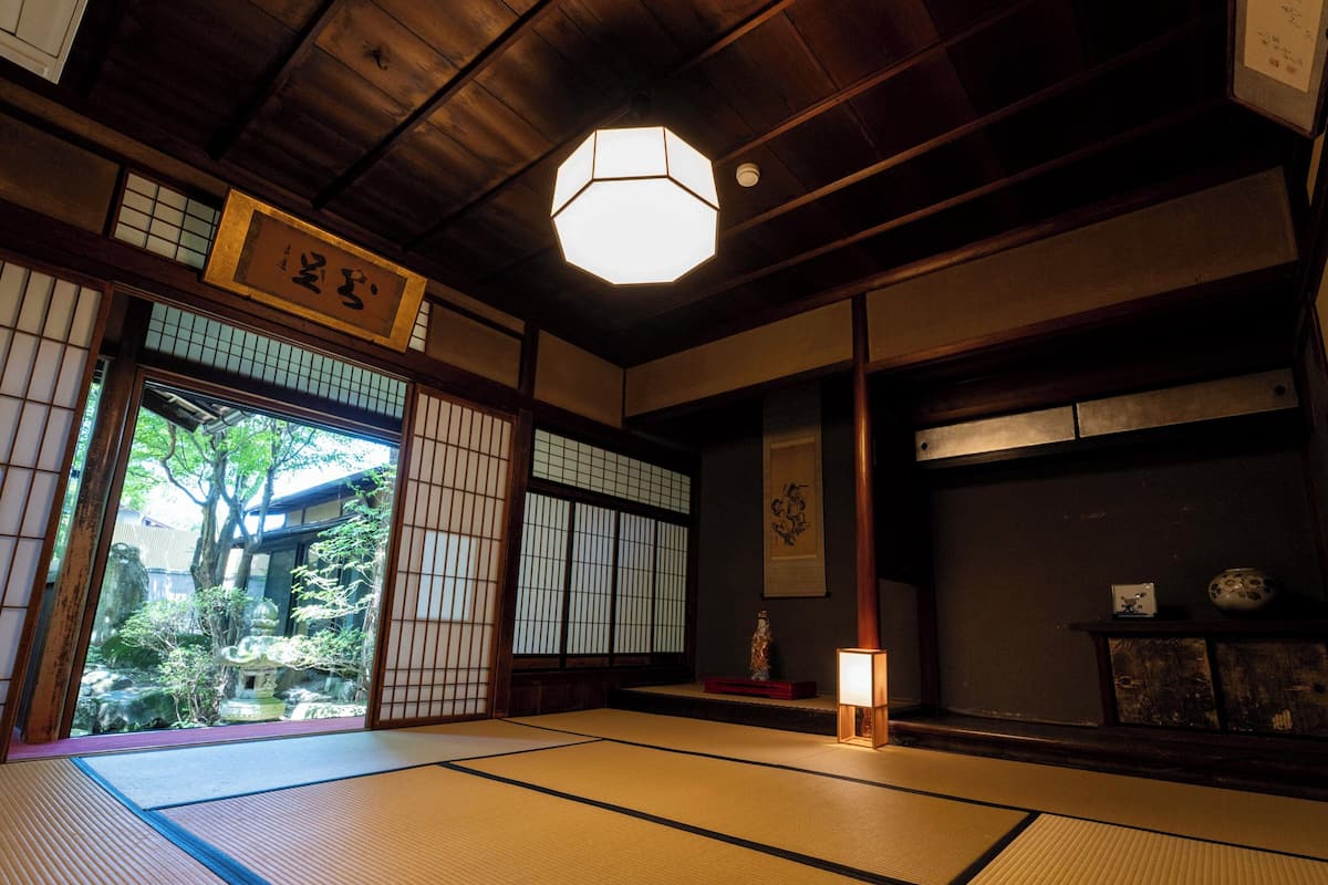 Una habitación japonesa tradicional con suelo de tatami, puerta corredera shoji y un farol colgante.