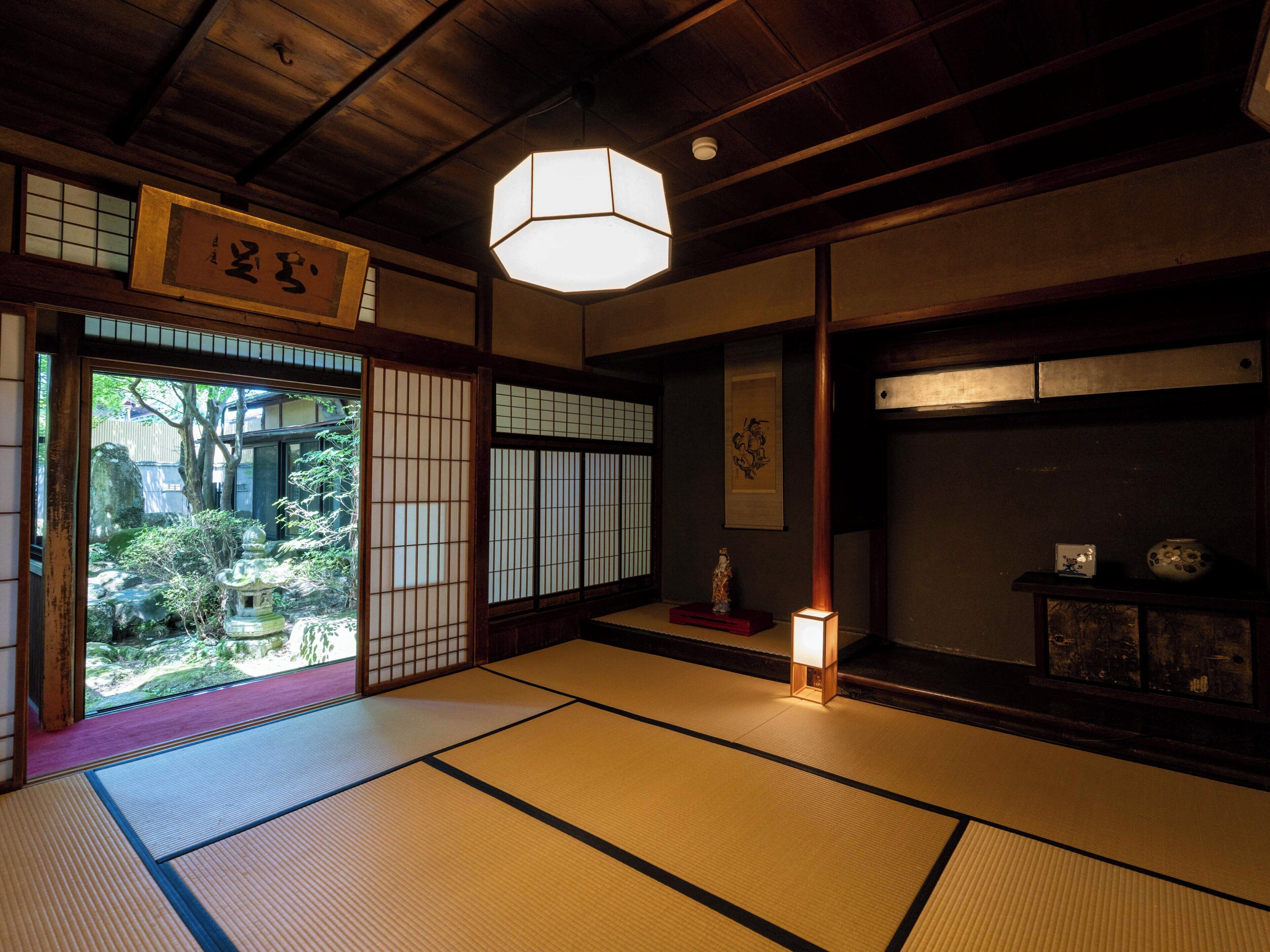 Ett traditionellt japanskt rum med tatamimattor på golvet, en skjutdörr av rispapper (shoji) och en hängande lykta.
