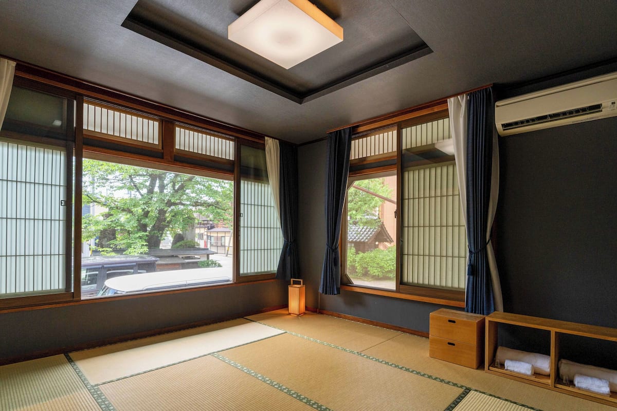 Una habitación japonesa tradicional con suelo de tatami, puertas correderas shoji y una lámpara de techo.