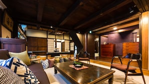 A traditional Japanese-style living room with tatami flooring, a low wooden table, and a sofa with cushions. - Temple Hotel Takayama Zenkoji (Takayama)