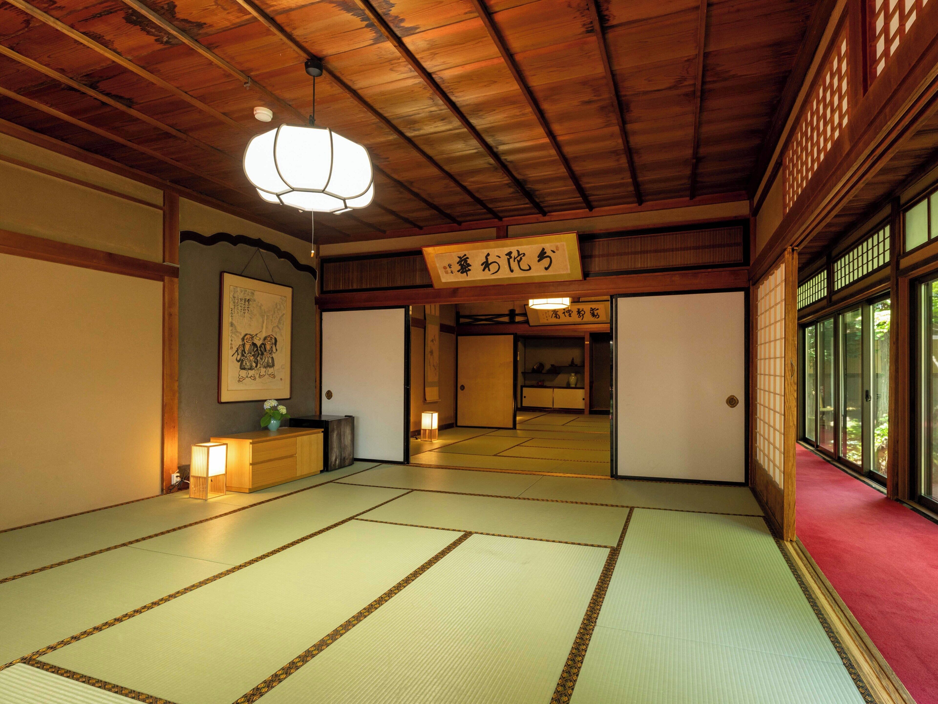 A traditional Japanese room with tatami flooring, a hanging light fixture, and sliding doors.