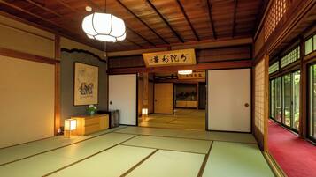 A traditional Japanese room with tatami flooring, a hanging light fixture, and sliding doors.