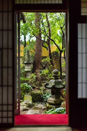 Step into a serene Japanese garden through a traditional lattice door, featuring stone lanterns and a majestic torii gate.