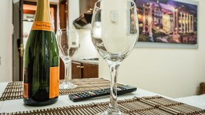 A bottle of Veuve Clicquot champagne and an empty glass on a table with a remote control and a painting in the background. - Termini Guesthouse (Rome)