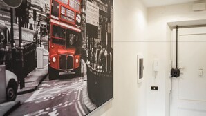 A hallway with a large black and white photograph of a red double-decker bus and a white door. - Termini Guesthouse (Rome)