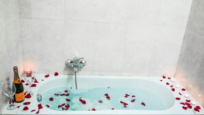 A bathtub filled with water and rose petals, a bottle of champagne, and two glasses. - Termini Guesthouse (Rome)