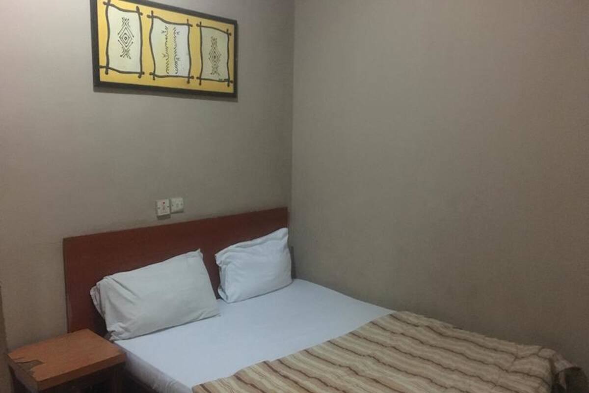 A simple room with a bed, a nightstand, and a wall-mounted artwork.