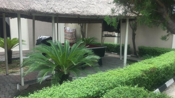 A covered outdoor area with a pool table, a thatched roof, and lush greenery. - Villa Savoye Hotels and Resorts (Lekki)