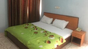 A bedroom with a bed, a nightstand, a telephone, and a framed picture on the wall. - Villa Savoye Hotels and Resorts (Lekki)