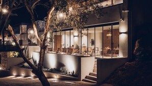 Une maison moderne dotée d’une grande façade vitrée, d’un espace extérieur aménagé pour se détendre et d’un jardin bien éclairé.