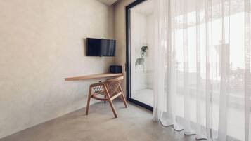 Una habitación moderna con un televisor de pantalla plana en la pared, un escritorio de madera y una silla de mimbre.