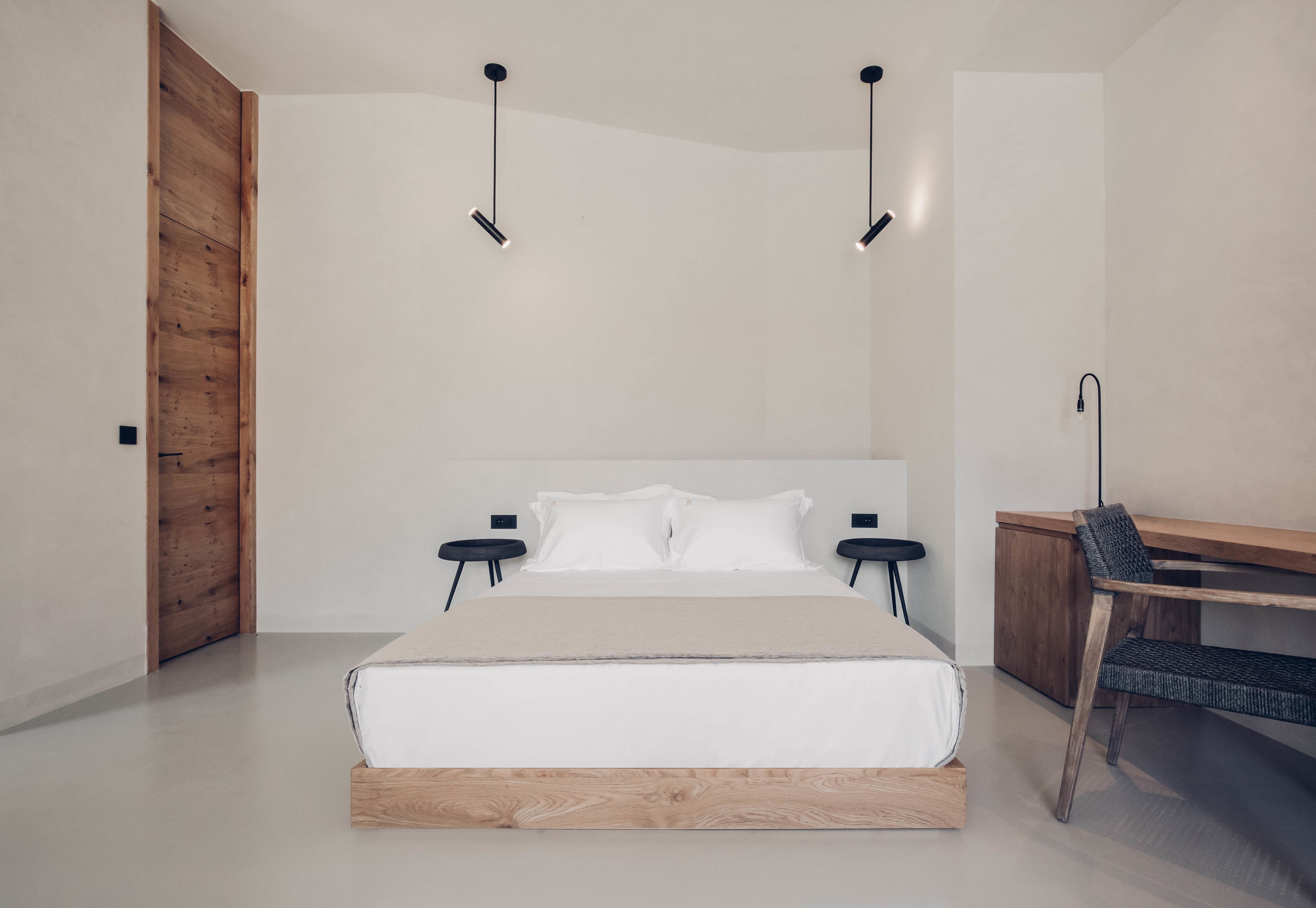 A modern bedroom with a large bed, bedside tables, a desk, and a chair.
