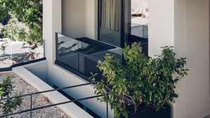 Un bâtiment moderne doté d’un balcon, d’une grande fenêtre et d’une plante en pot.