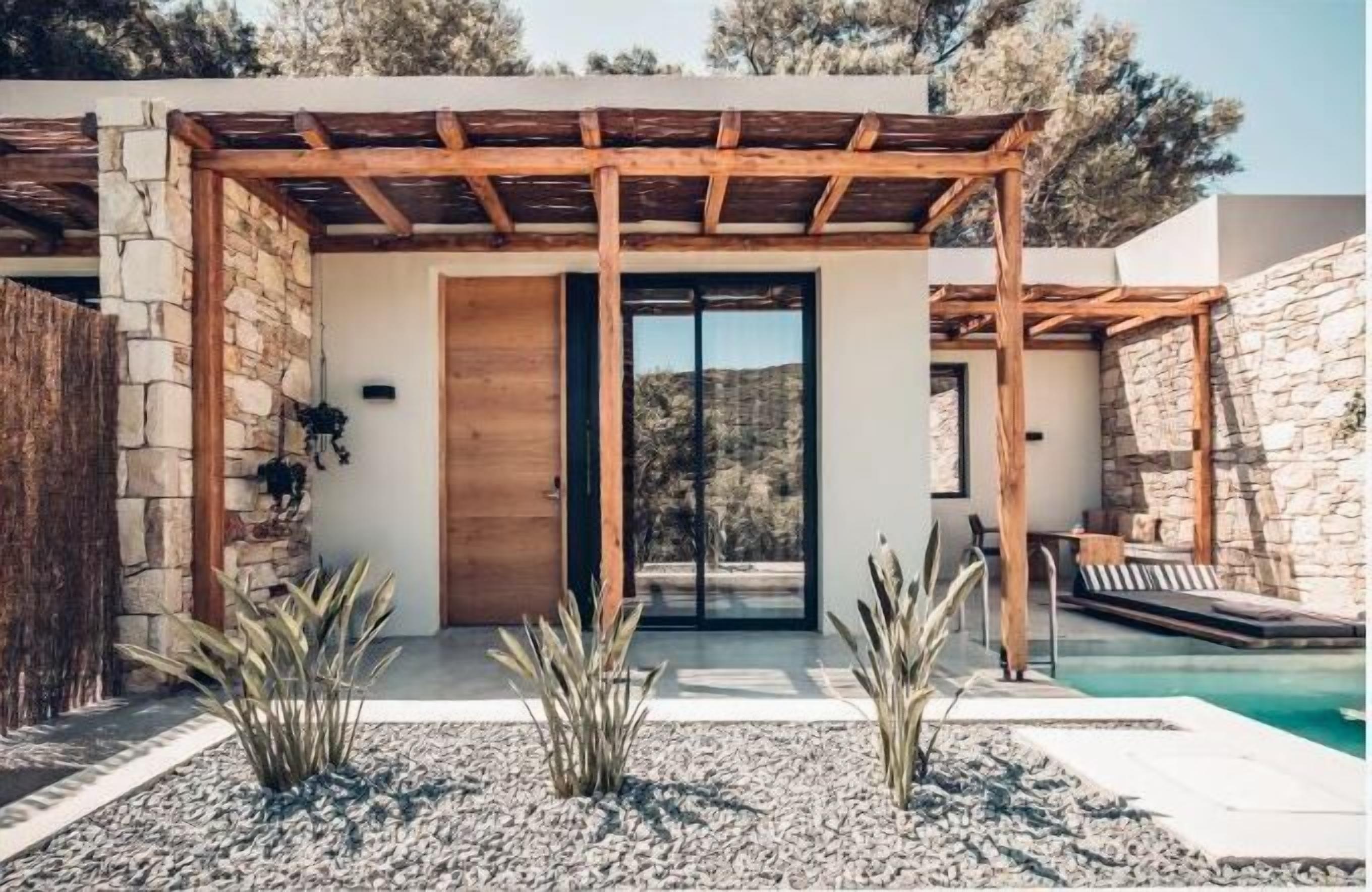 Un espace piscine extérieur moderne, agrémenté d’une pergola en bois, de murs en pierre et offrant une vue dégagée sur le paysage environnant.