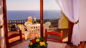 A balcony with a table and chairs, a view of the sea, and a bouquet of flowers. - Stintino Country Paradise (Stintino)