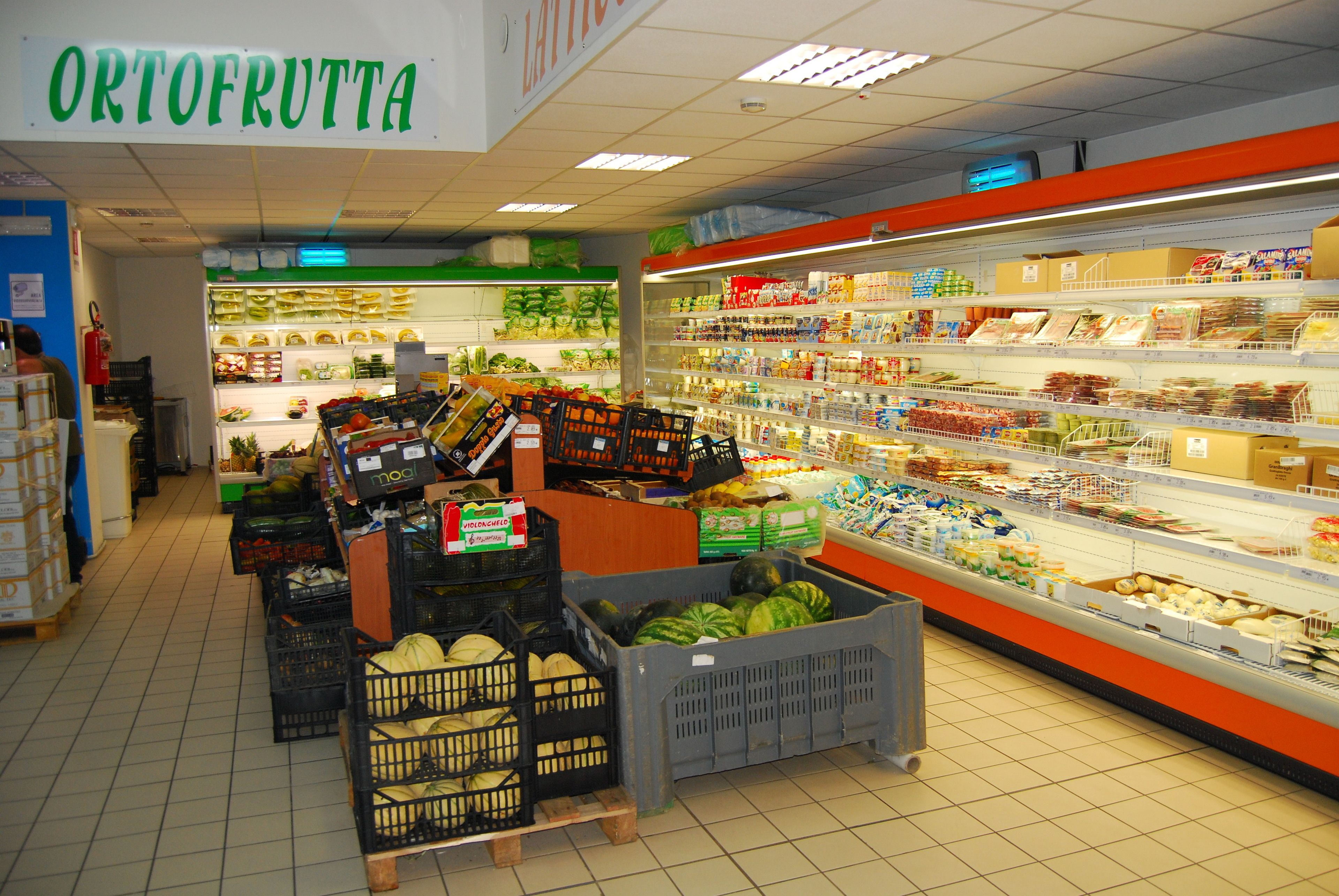 A grocery store interior with a section labeled 'ORTOFRUTTA' and various produce and packaged goods on shelves.