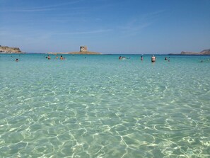 Un mar turquesa y transparente con gente nadando y tomando el sol.