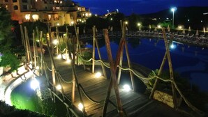 A nighttime view of a resort with a wooden deck, a swimming pool, and a building in the background. - Stintino Country Paradise (Stintino)