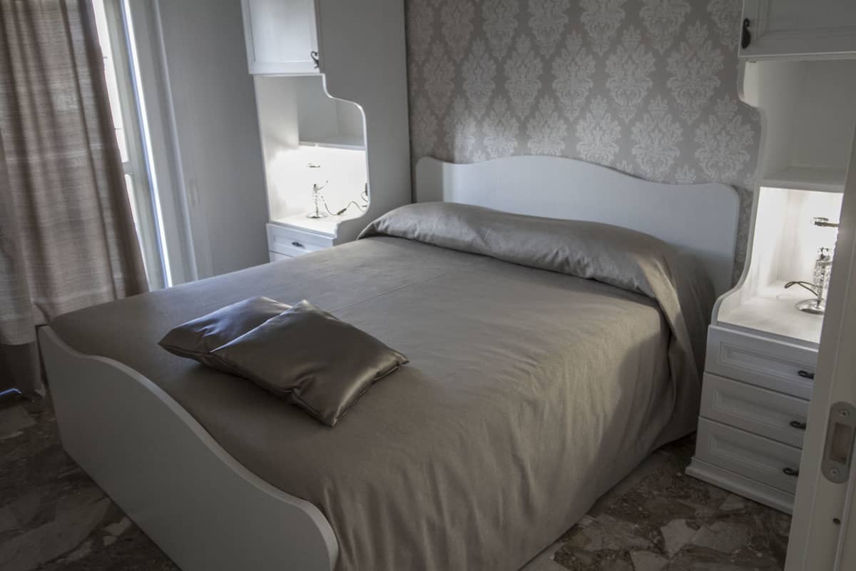 A modern bedroom with a bed, nightstands, and a dresser.