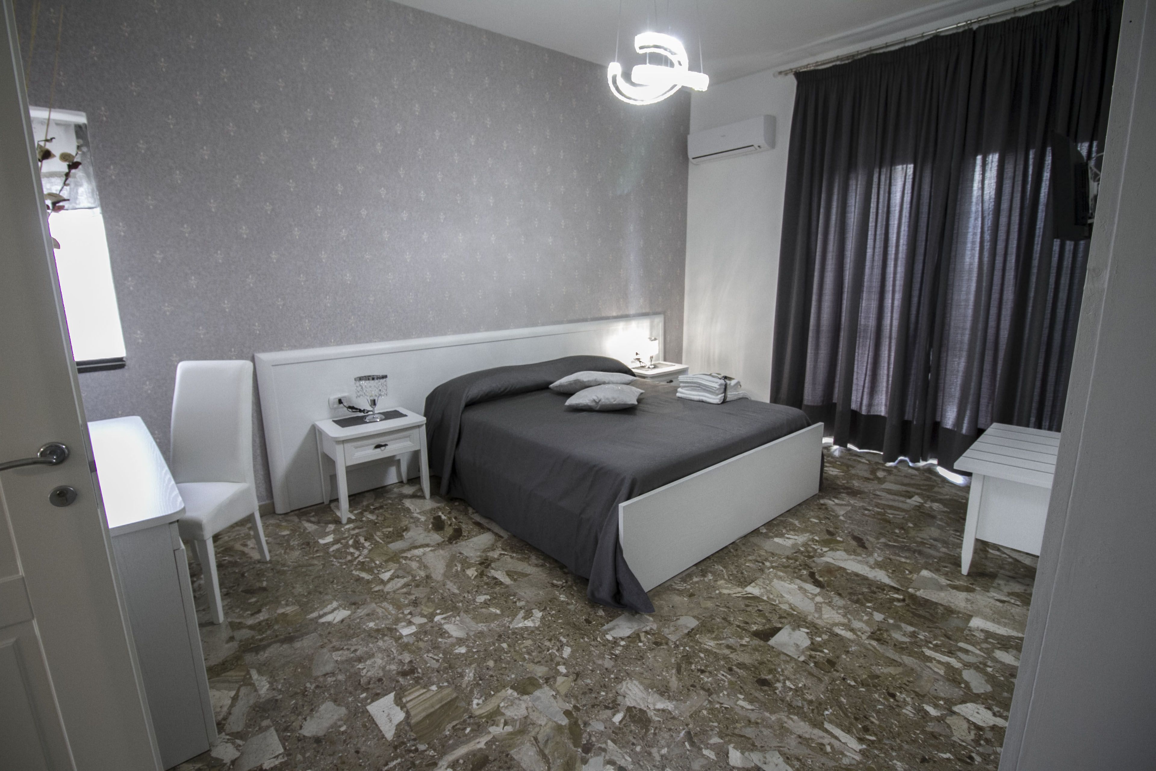 A modern bedroom with a bed, bedside table, chair, and a unique light fixture.