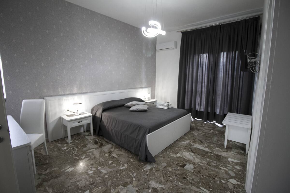 A modern bedroom with a bed, nightstand, and a small table.