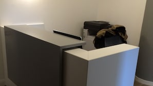 Un mostrador de recepción con superficie plana, un pequeño mostrador y una impresora.