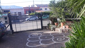 Una entrada con portón y un camino de entrada pavimentado que conduce a un edificio con tejado de tejas.